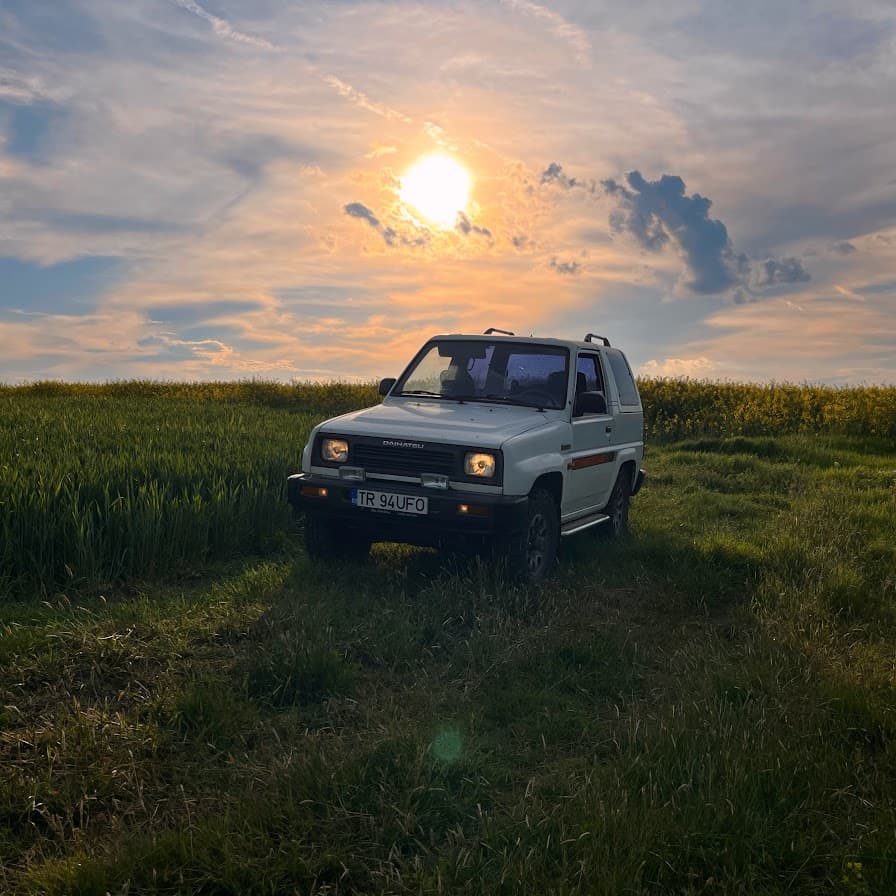 A white 1994 Daihatsu Feroza in a field at sunset