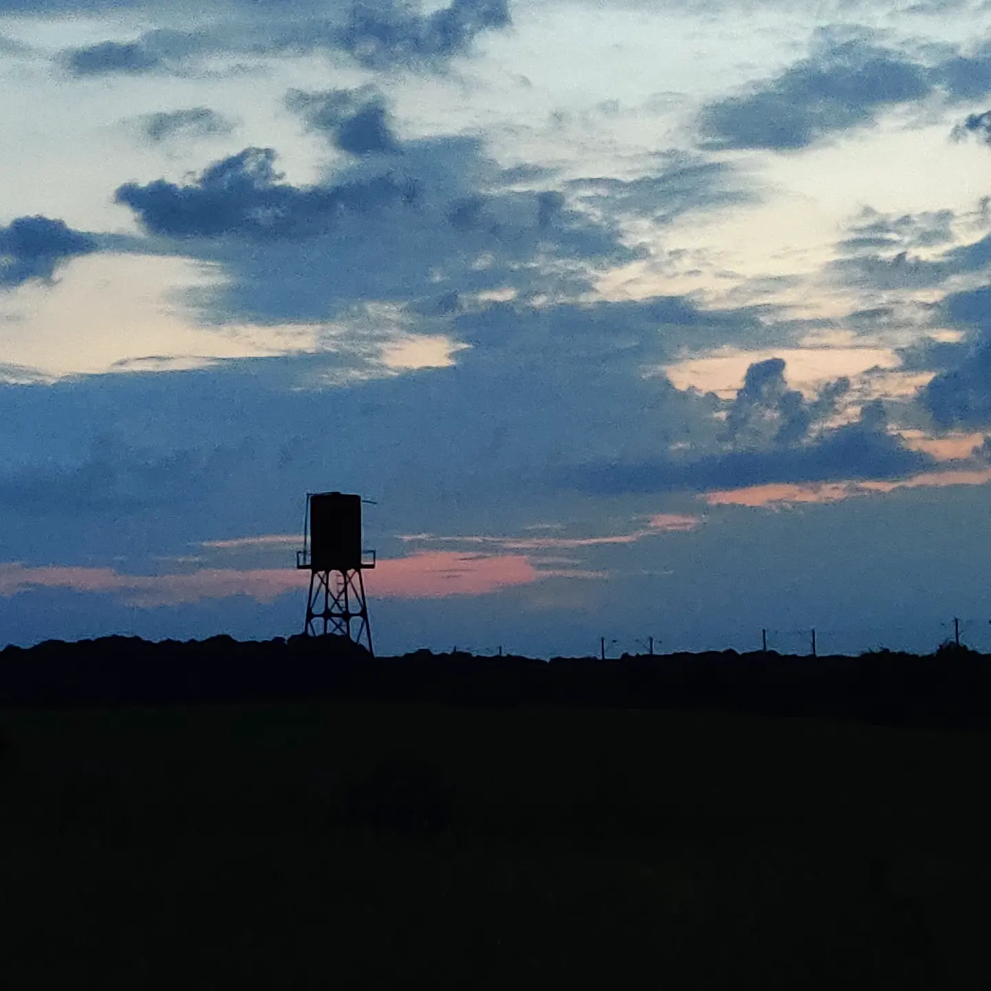 A water tower silhouetted on the horizon at dusk
